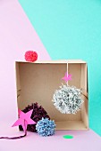 Pompoms arranged in old box in front of two-tone wall
