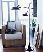 Wicker armchair with seat cushion next to black standard lamp