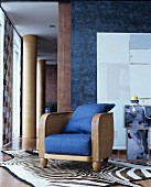 Rattan and wood lounge chair with blue cushions on zebra-skin rug