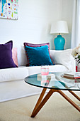 Round coffee table in front of white sofa with velvet cushions in shades of blue and purple