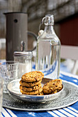Silver dish of biscuits and swing-top bottle on garden table