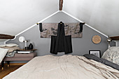 Double bed in attic room with Japanese Haori hung on grey wall