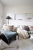 Various blankets and cushions on récamier and sofa under pictures on wall