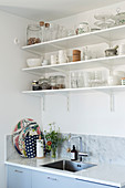 Crockery and groceries on open kitchen shelves above sink