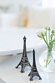Two small Eiffel towers next to vase of ranunculus