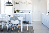 Esstisch mit verschiedenen Stühlen in heller Wohnküche