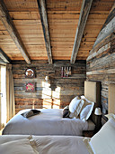Twin beds in rustic bedroom with wooden walls