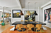 Schwarzer Esstisch mit Klassikerstühlen vor weiss gestrichener Ziegelwand in offenem Wohnbereich