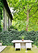 Steintisch mit Stühlen vor Hecke auf der Terrasse