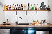 House bar: counter with sink, wooden shelf above with drinks