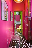 Blick vom Flur mit pinken Wänden und bemaltem Boden in die Küche