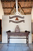 Buddha statue on antique wooden table against partition wall