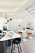 Runder Esstisch und Designerstühle in der offenen Küche mit Balkendecke