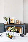 View across dining table to fireplace surrounded by dove grey wainscoting