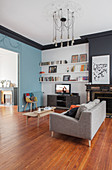 Bookcase, TV cabinet, sofa and coffee table in living room with dove-grey accent wall