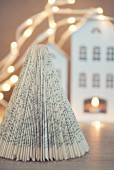 Christmas tree made from folded book pages in front of house-shaped lantern