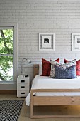 Modern wooden bed against white brick wall