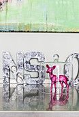Pink, glittery fawn under glass cover and decorative letters on glossy surface