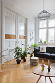 Sofa and houseplants in front of double doors in period apartment