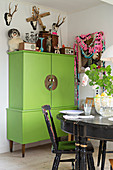 Black dining set in front of green cabinet and kitsch decorations