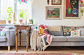 Antique side table between two sofas draped with crochet blankets