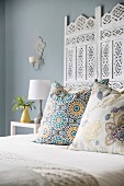Scatter cushions on white double bed with ornate headboard