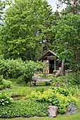 Rustikaler Holzbank mit Blick auf den Gartenteich, im Hintergrund Orangerie