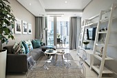 Eleganter Wohnbereich mit Polstercouch, Ghost-Chairs und weißem Leiterregal