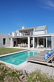 Pool and lawn outside elegant holiday home beneath blue sky