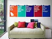 Colourful graphic-design posters above comfortable sofa with various scatter cushions