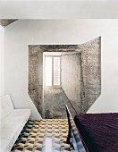 Unusual composition of window in concrete wall in bedroom with geometric floor tiles