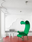 Green, whimsical wicker armchair on red floor of white loggia
