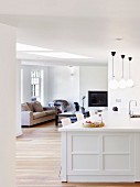 weiße Kücheninsel und Blick in reduzierten Wohnbereich