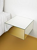 Mirrored floating bedside cabinet mounted on wall next to bed