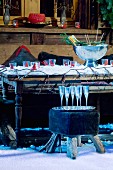 Verschneiter Holztisch mit Sektkühler und rustikaler Polsterhocker mit Sektgläsern vor Chalet