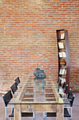 Dining table with glass top and metal chairs in front of brick wall