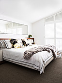 Double bed with pillows, large mirror above in white living room
