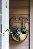 Golden plant bowl and vintage letters on wooden wall