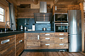Modern kitchen with rustic wooden cupboards and stainless steel fridge