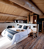 Bett mit Betthaupt als Raumteiler im Schlafzimmer unter dem Dach