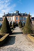 View of Château Les Aulnois between conical clipped hedges