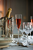 Roter Champagner im Glas vor silbernem Flaschenkühler