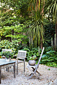 Weathered garden furniture on gravel terrace in wild garden