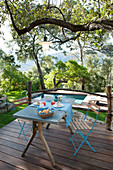 Set breakfast table on wooden terrace with swimming pool in background