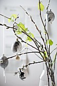 Marbled Easter eggs hung from willow and beech branches in vase
