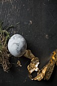 Easter egg painted with stone effect and gold leaf on black-painted wood