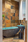 Slate tiles and pebble-shaped bathtub in rustic bathroom