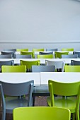 Green and grey chairs at white tables in canteen