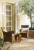 Two wicker armchairs and wooden table on Mediterranean terrace