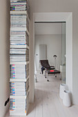 Magazines on vertical shelves next to open doorway with view of brown armchair